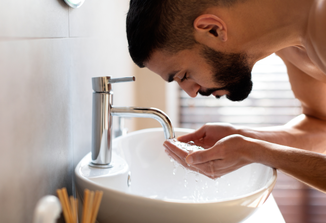 Man with beard rinsing his face